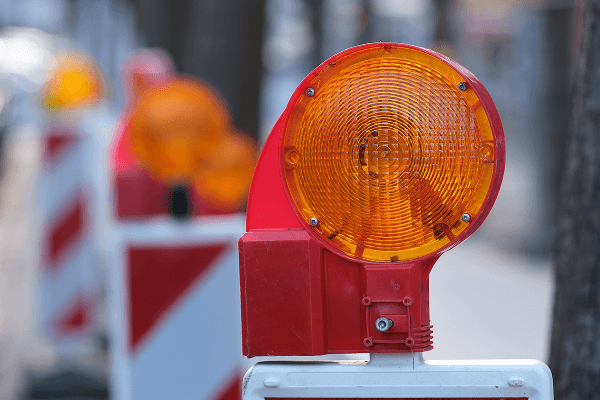 Flashing orange light sits atop a traffic barricade.